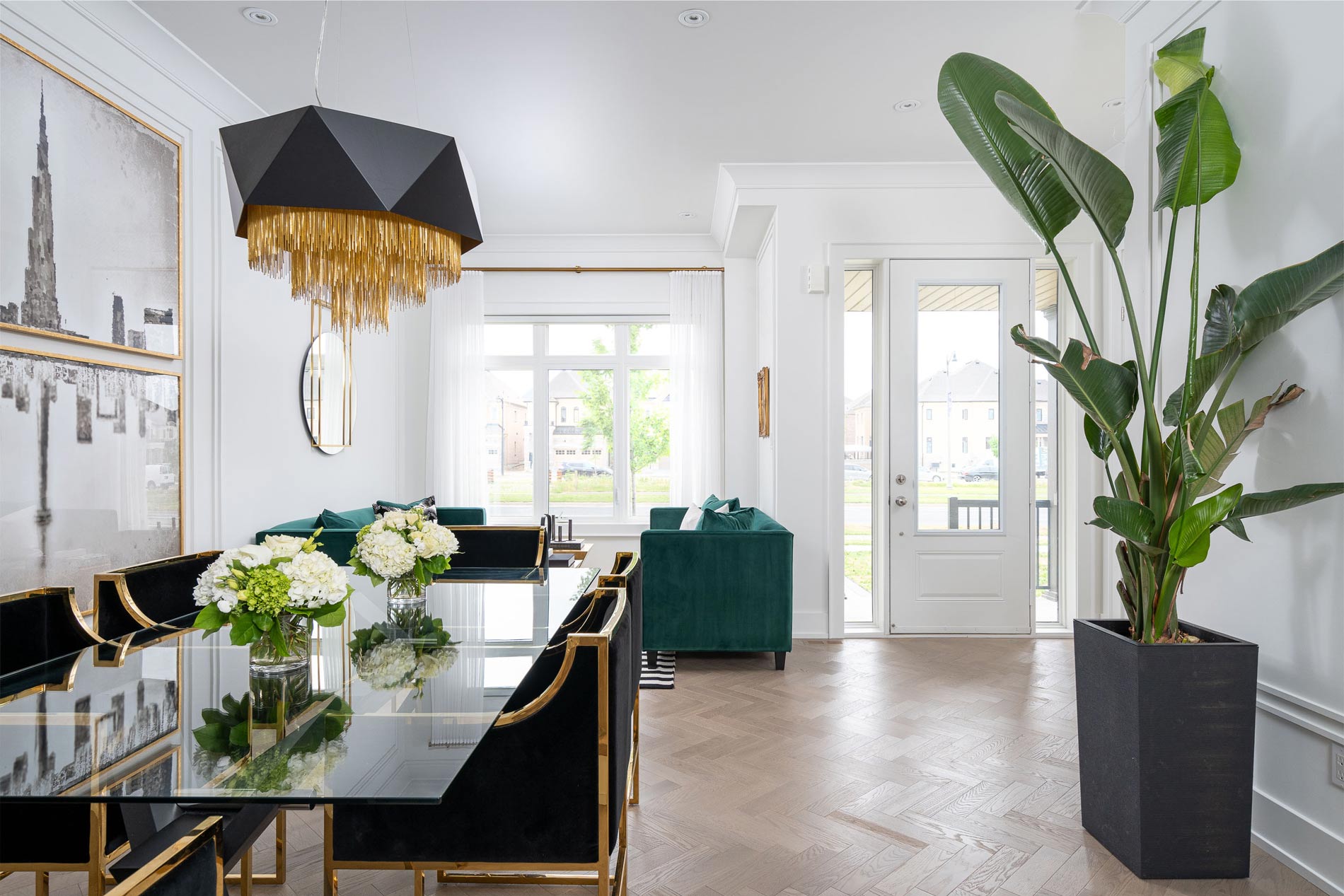 Bright dining and living room with emerald velvet seating and a glass table